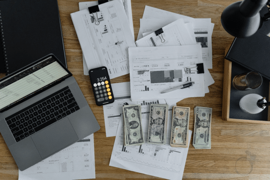 Laptop_with_paperwork_and_money_on_a_table